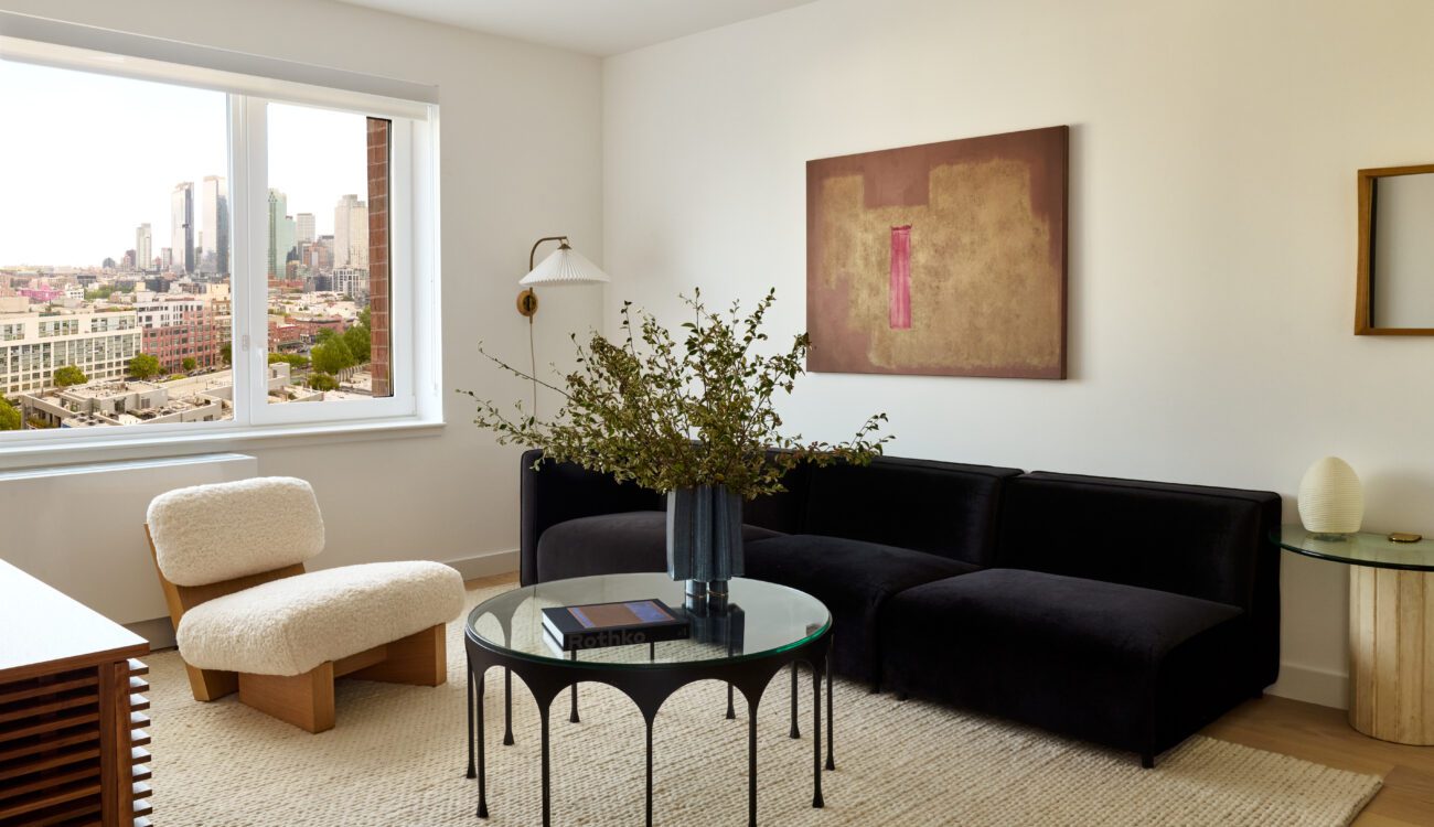 Living Room in Long Island City with a black couch, white chair, and coffee table