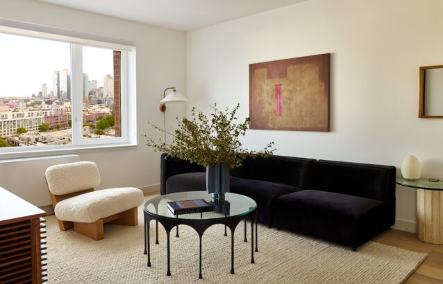Living Room in Long Island City with a black couch, white chair, and coffee table